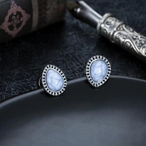 Detailed view of teardrop stud earrings with white marble stone and vintage engraved edges