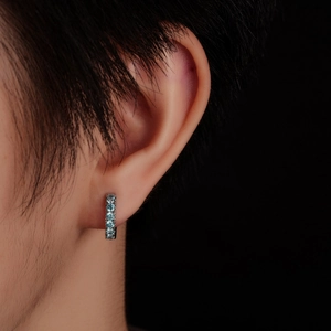 Close-up of small silver hoop earring set with five brilliant light blue stones on ear