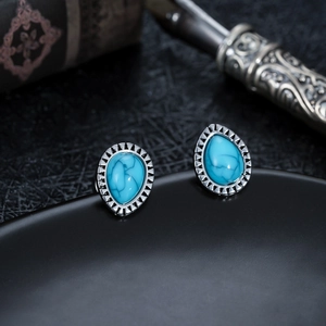 Detail of vintage teardrop stud earrings with blue turquoise inlay and textured silver frame