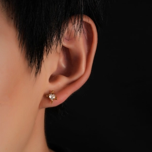 Gros plan sur un clou d'oreille en titane doré avec cœur croix et zircon