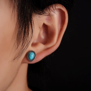 Macro shot of vintage teardrop earrings with turquoise stone and geometric silver base