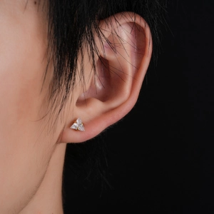 Detailed close-up of a triangle-cut zircon stud earring with a gold-tone screw back setting