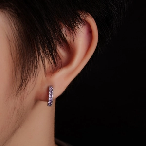 Macro shot of silver huggie earrings featuring row of sparkling round cut purple stones
