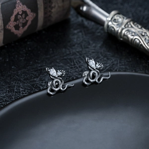 Détail de boucles d'oreilles serpent en argent avec pierres précieuses sur support noir