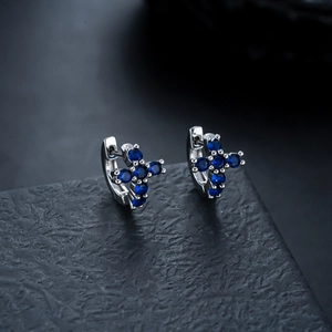 Detail of silver cross hoop earrings with inlaid dark blue cubic zirconia stones