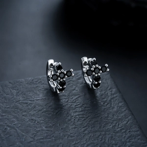 Macro shot of silver cross earrings with black cubic zirconia and secure ring closure