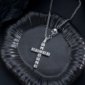 Close-up of vintage silver cross pendant with skull detail and PEACE engraving