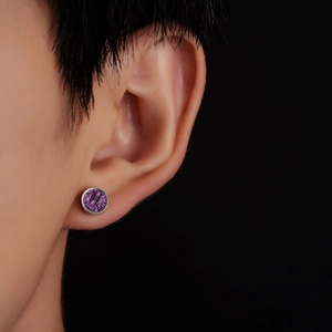 Macro view of round silver stainless steel stud earring with purple glitter texture