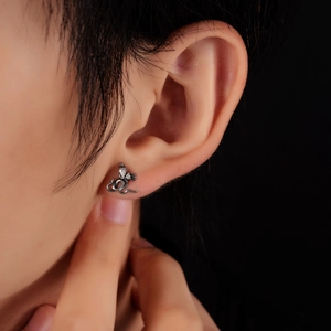 Boucles d'oreilles serpent en acier avec zircons portées par un mannequin sur fond sombre