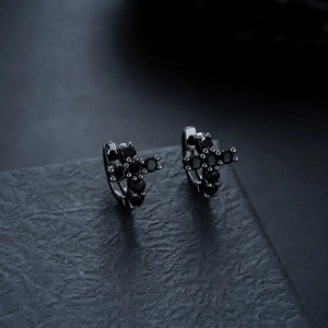 Detailed macro view of black plated cross earrings with sparkling black zircon stones