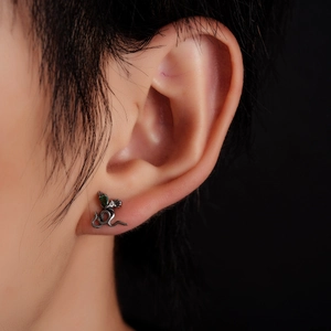 Gros plan d'un clou d'oreille serpent en titane avec une pierre verte sur l'oreille