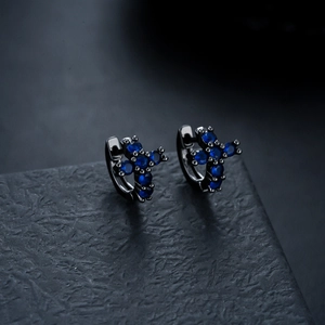 Detailed macro view of black metal hoop earrings featuring blue zircon cross design