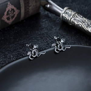 Gros plan de boucles d'oreilles serpent gothiques avec gemmes noires sur livre