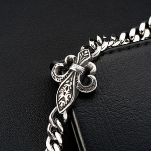 Macro detail of vintage fleur-de-lis stainless steel curb chain bracelet with oxidised finish