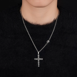 Silver cross pendant necklace with skull detail and engraved text on black knitwear