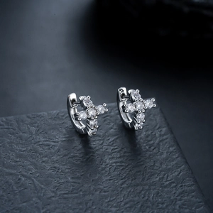 Macro shot of silver cross hoop earrings with sparkling cubic zirconia on stone base