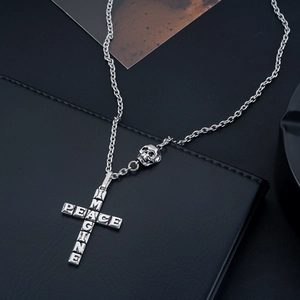 Macro shot of silver cross pendant with PEACE IMAGINE letters and skull on black leather