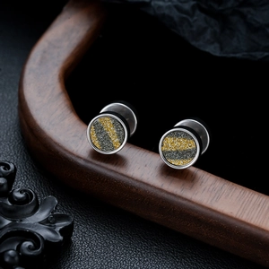 Macro view of silver titanium steel studs with gold and black glitter diagonal stripes