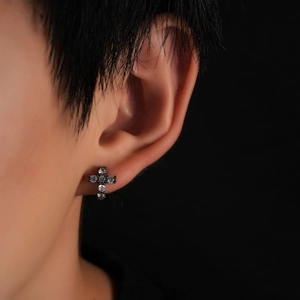 Black cross zircon earrings with sparkling crystals worn by a model on dark background