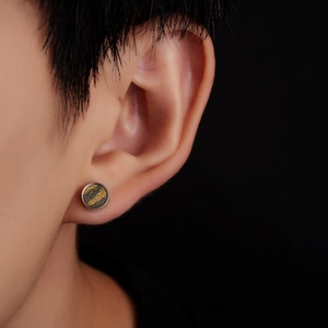 Macro shot of titanium steel stud earring with yellow and black texture on male ear