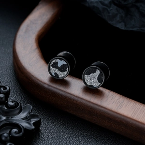 Macro shot of black titanium steel stud earrings featuring silver glitter camouflage pattern