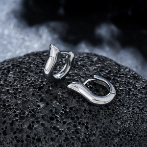 Polished silver titanium steel geometric hoop earrings on dark volcanic rock