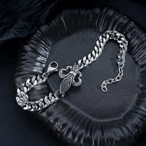 Close-up of vintage steel Cuban chain bracelet with Fleur-de-lis charm and lobster clasp