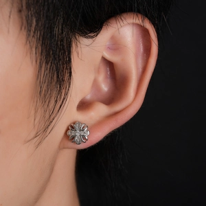 Close-up of zircon-inlaid cross flower stud earring on ear with silver finish
