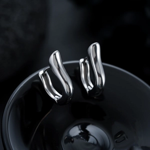 Macro shot of silver titanium steel earrings with irregular geometric fluid design