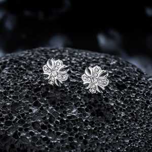 Macro shot of silver iris cross stud earrings with sparkling zircons on black stone
