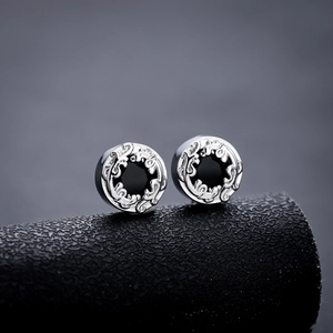 Macro shot of silver stud earrings with black center stone and vintage engraved patterns