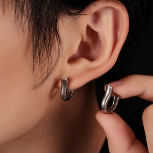 Macro shot of a silver U-shaped titanium hoop earring showing modern hinged mechanism