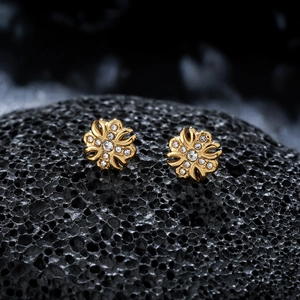 Macro shot of gold floral stud earrings with cubic zirconia on black stone base