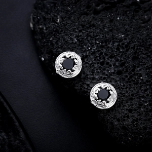 Baroque style silver stud earring with center black stone on volcanic rock background