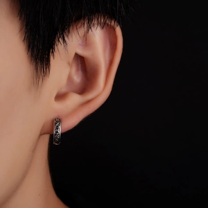 Close-up of vintage titanium steel hoop earring with engraved vine pattern on model