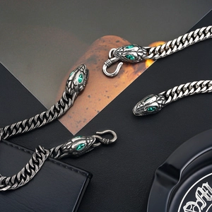 Close-up of vintage silver curb chain with green crystal-eyed snake head clasp