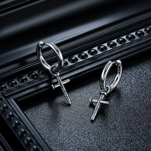Detailed close-up of gothic cross hoop earrings with punk spike texture on black leather