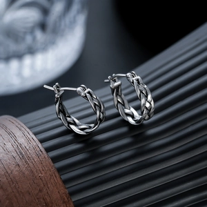 Vue détaillée de boucles d'oreilles créoles en acier titane avec texture tressée rétro