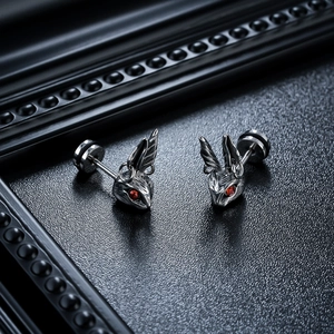 Close-up of punk rabbit stud earrings with red zircon eyes on black vintage background