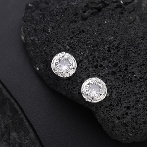 Macro shot of silver studs with cubic zirconia on black volcanic rock texture