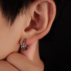 Gros plan sur une boucle d'oreille créole en acier titane avec motif torsadé