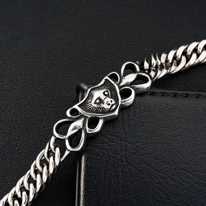 Macro detail of retro silver lion head medal on thick titanium steel curb chain