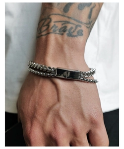 Detail of double-layered stainless steel curb and box link bracelet on wrist
