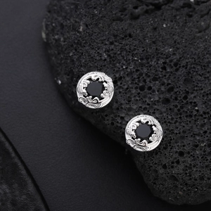 Macro view of vintage silver stud earrings with black zircon and ornate carvings