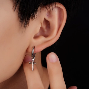 Macro shot of silver titanium cross earring with vintage nail texture on earlobe