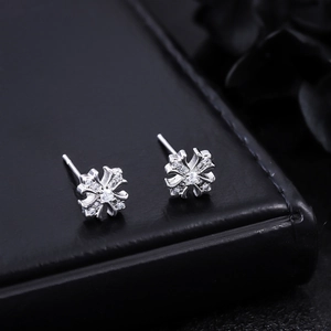 Gros plan de boucles d'oreilles croix iris en argent avec zircone sur boîte en cuir noir