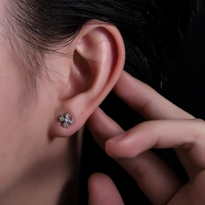 Gros plan d'un clou d'oreille croix gothique serti de zircons porté par un mannequin