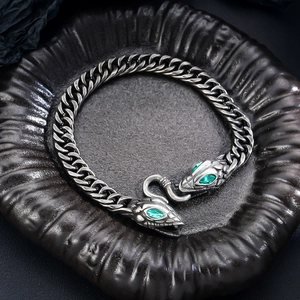 Close-up of double snake head bracelet with green zircon eyes and thick cuban chain