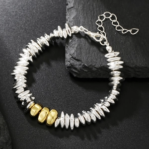 Polished silver hematite beads bracelet with gold accents on black stone surface