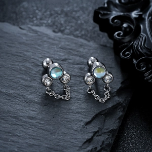 Détail de boucle d'oreille en titane avec pampille, opale et strass sur pierre noire